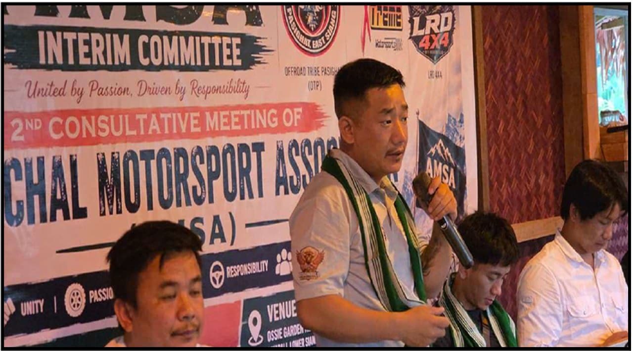 An office bearer addressing delegates in front of the Interim Committee backdrop at the 2nd Consultative Meeting.