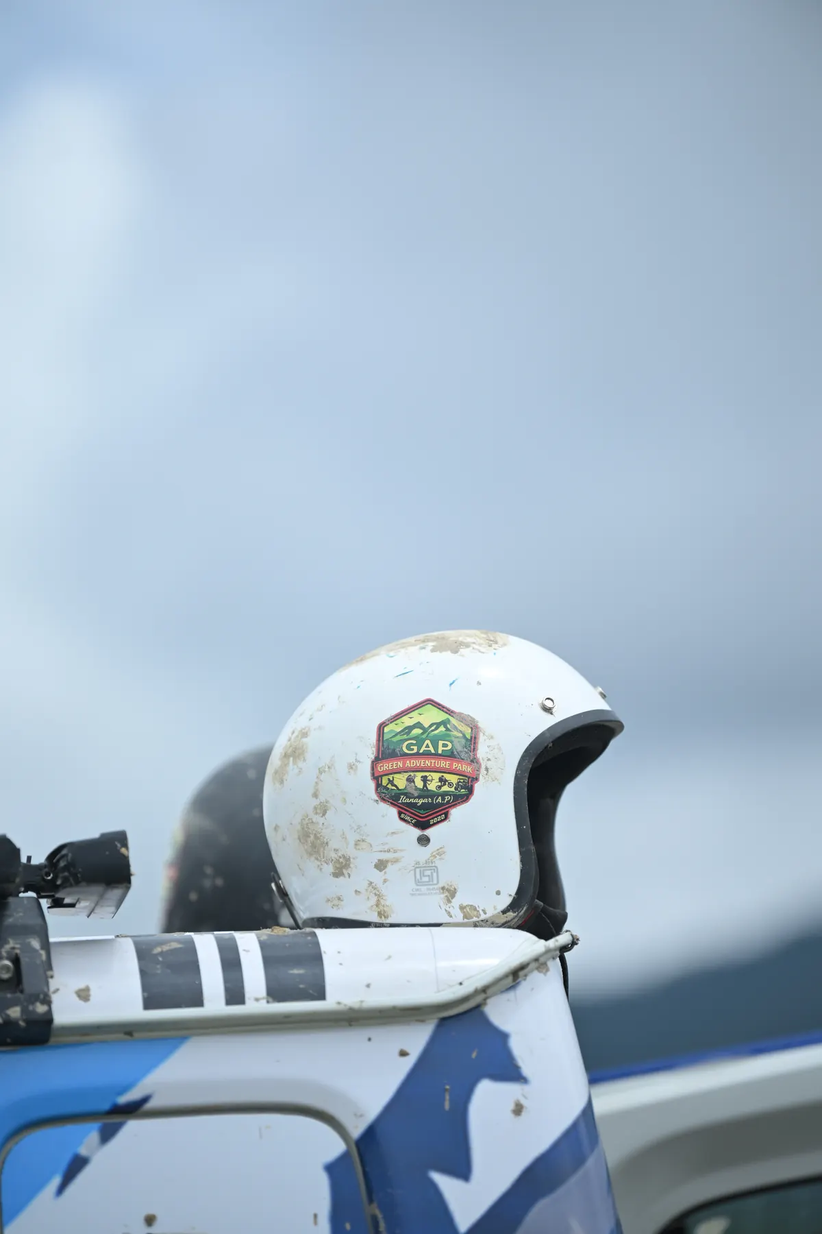 A white helmet with a club sticker resting on the roof of a vehicle.