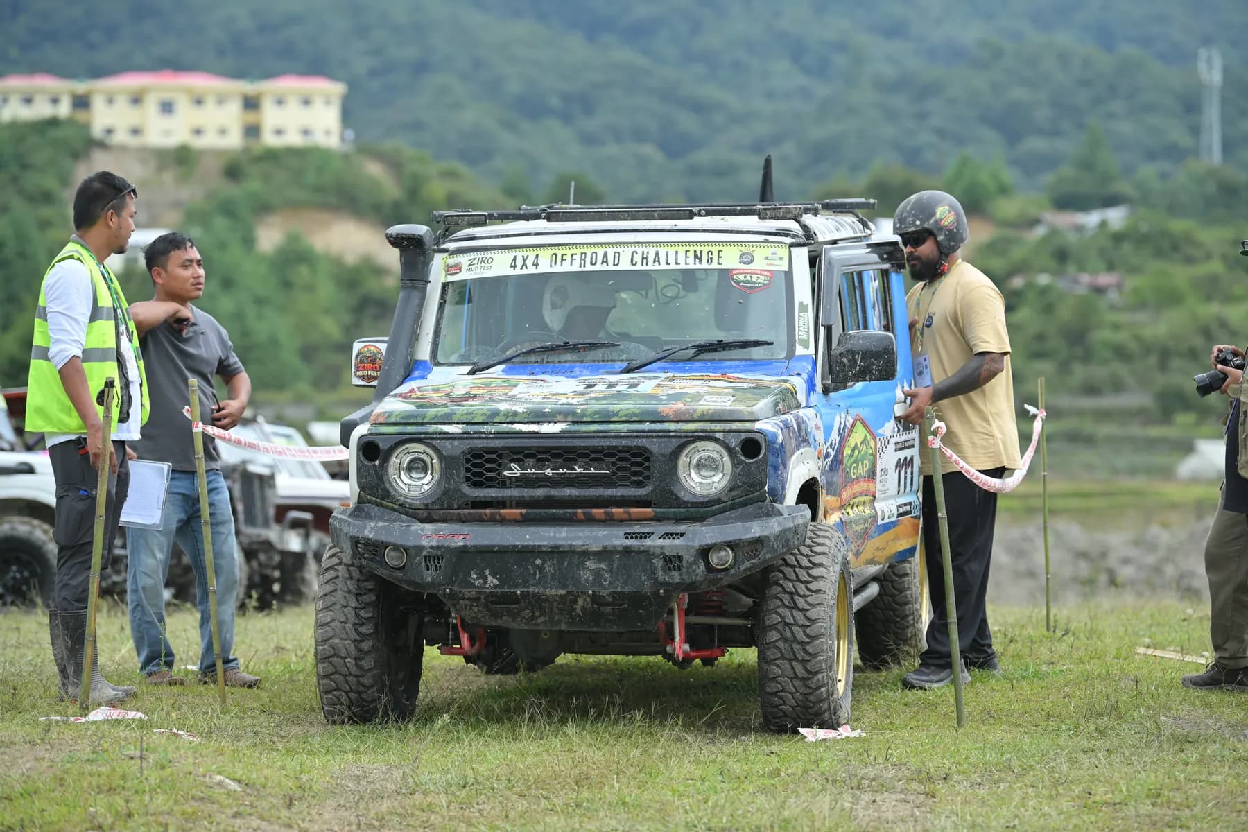 Marshals standing beside a liveried SUV at the edge of the course.