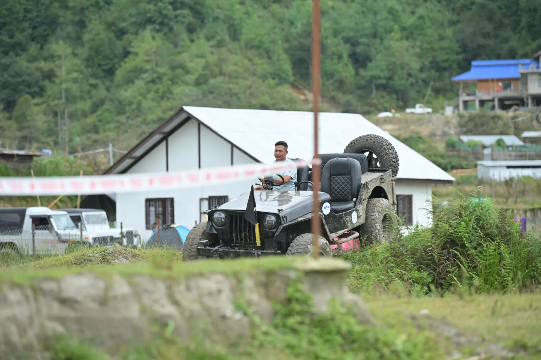 An open-top jeep driving past a white building on the course.