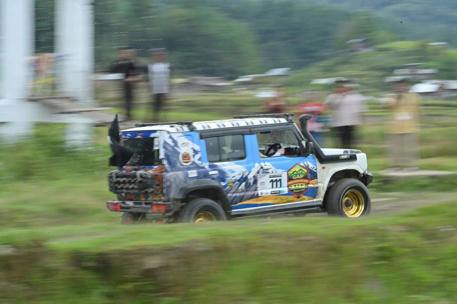 A rally-liveried SUV at speed, the background blurred by its motion.