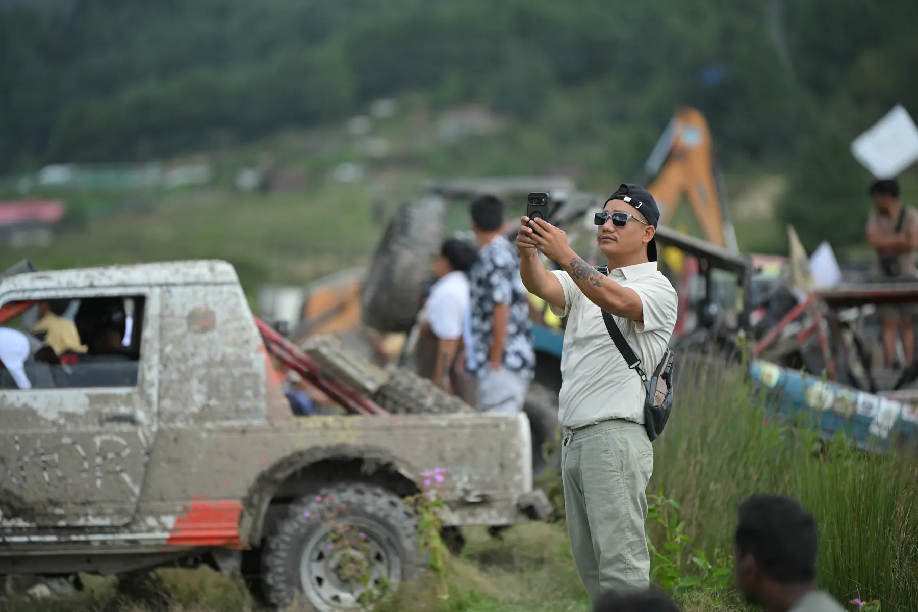 A mud-caked Gypsy beside a man taking a photograph with his phone.