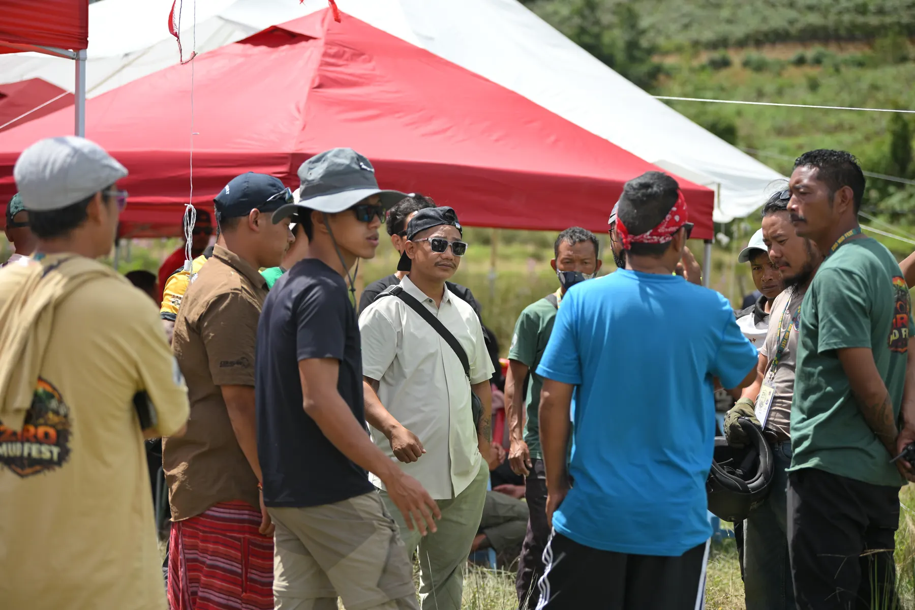 A group gathered under red canopies on the field.