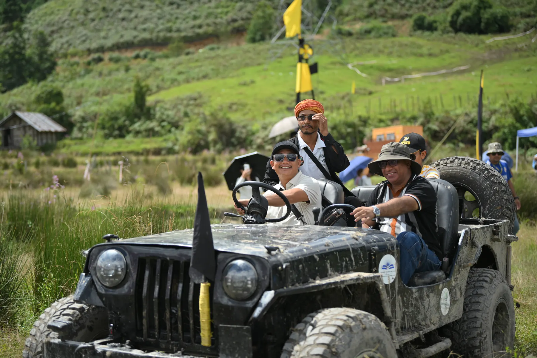 Two men in an open jeep carrying a black flag.