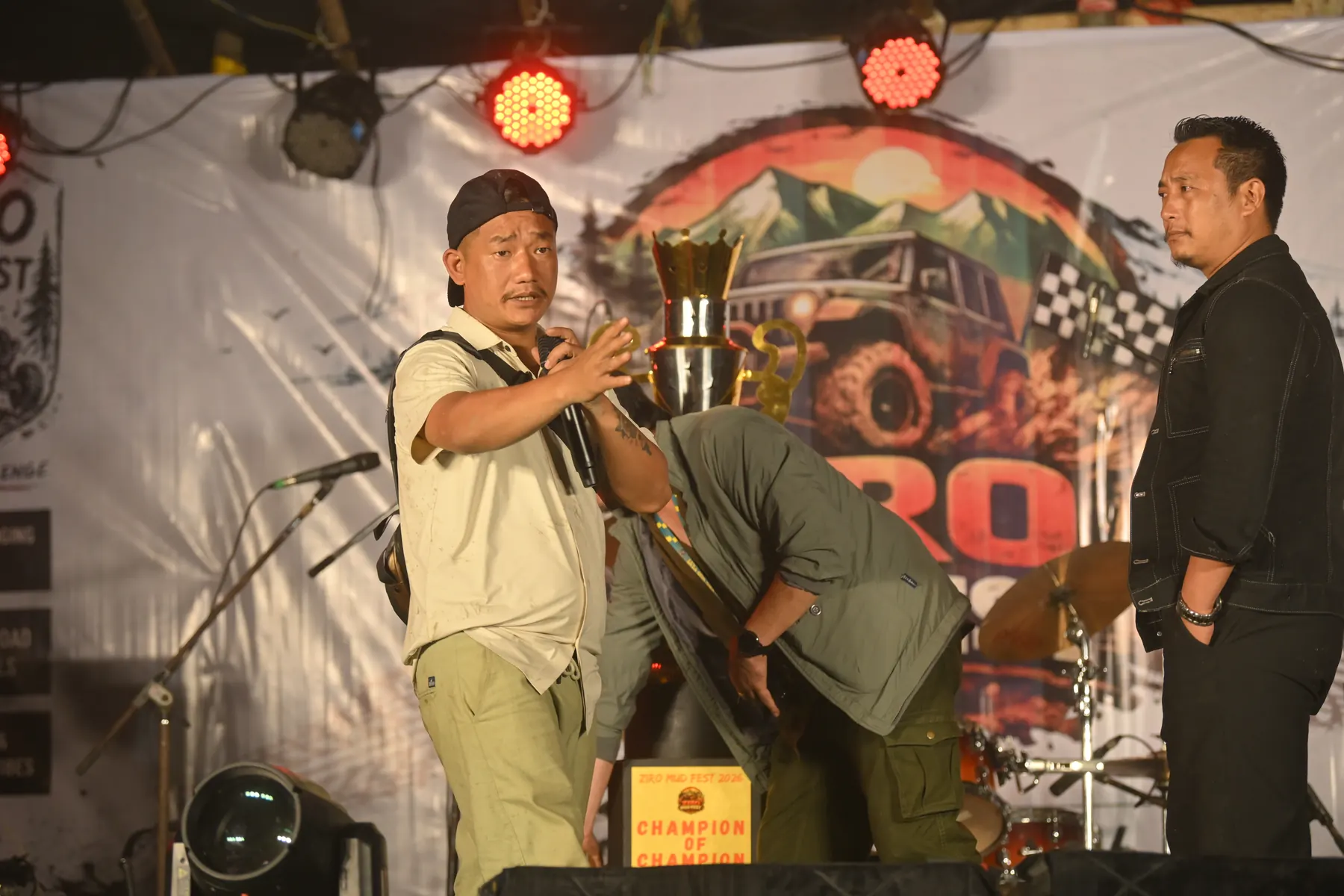 A man on stage at night holding up a trophy.