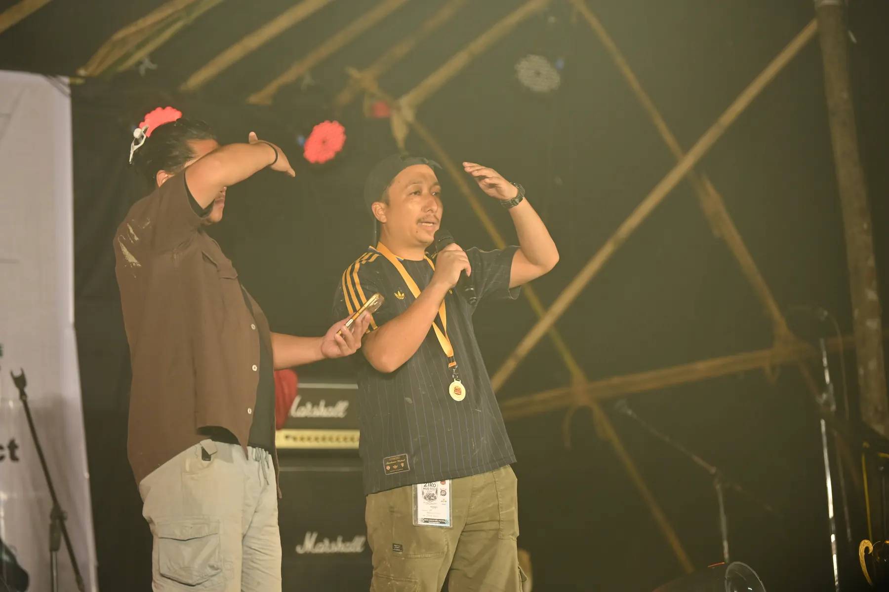 Two men on stage at night, one wearing a medal.