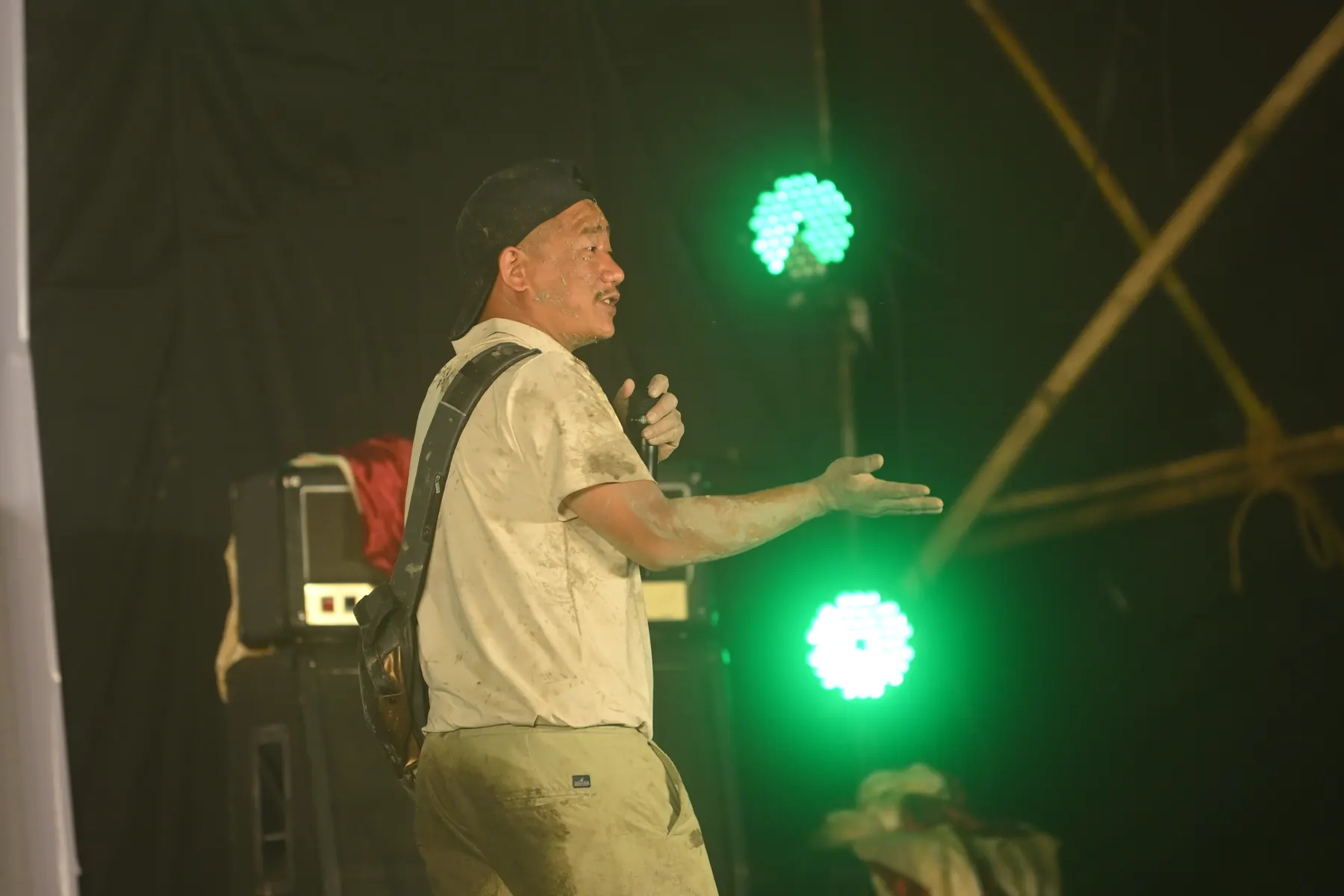 A man with a microphone on stage under green lights.